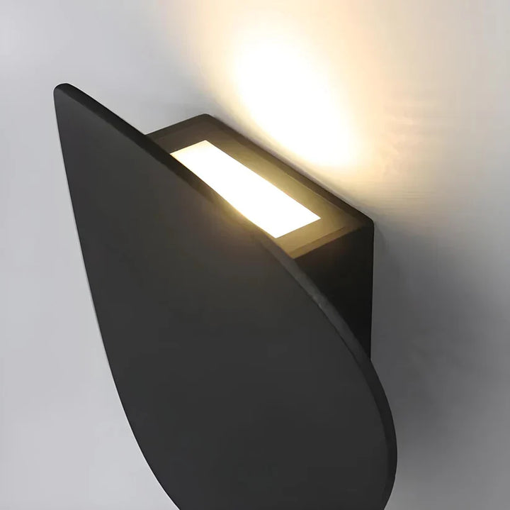 Close-up from above showing the lamp's rectangular light opening between the black disk and the wall mount. 10
