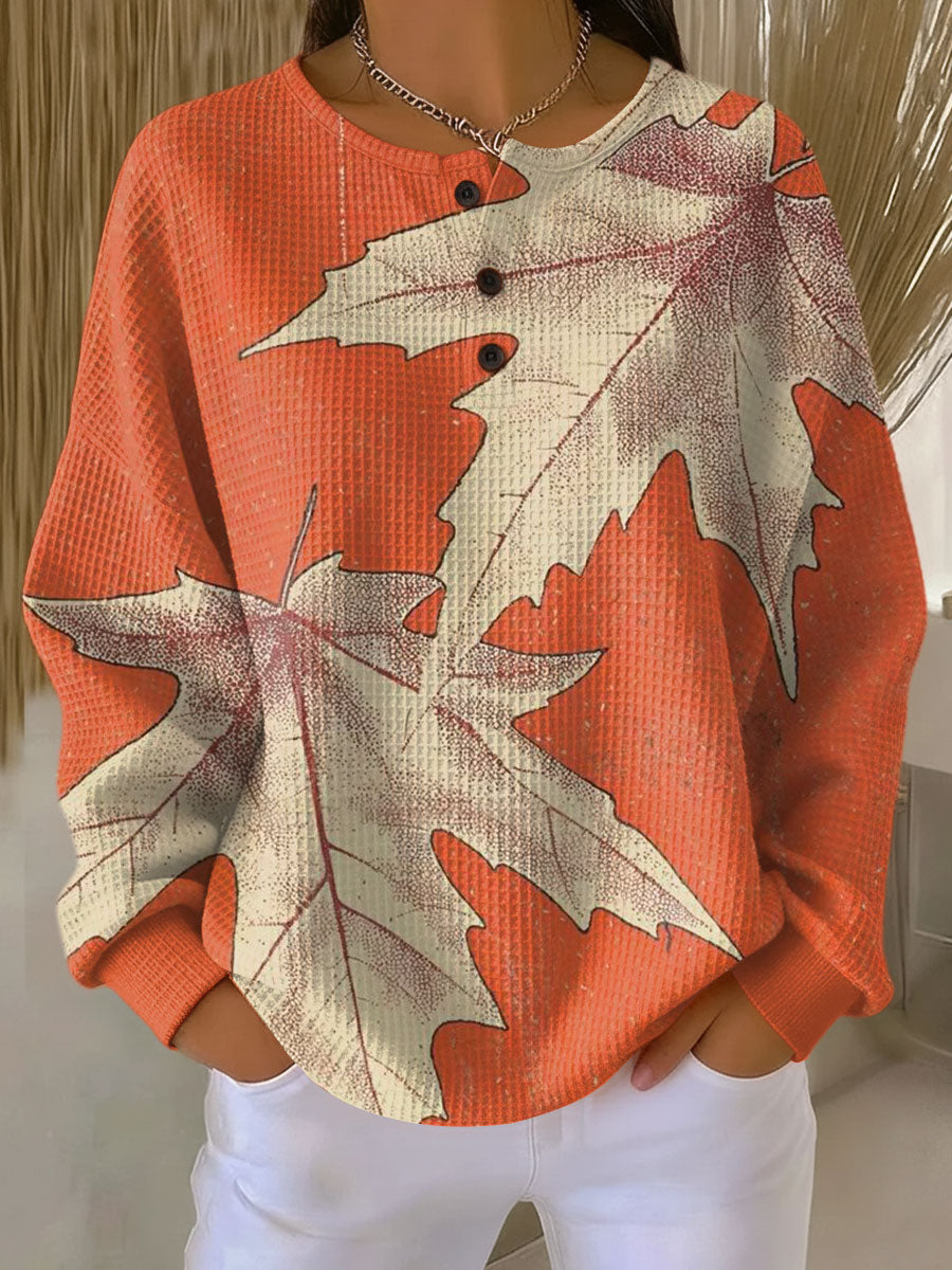 Orange waffle knit henley with large cream maple leaves printed across the front and sleeves 14