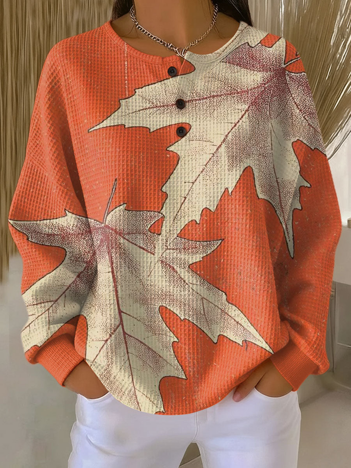 Orange waffle knit henley with large cream maple leaves printed across the front and sleeves 14