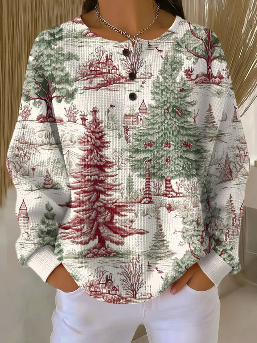 Cream waffle knit henley sweater with green and red winter forest print of pine trees and cottages, worn by a model 22