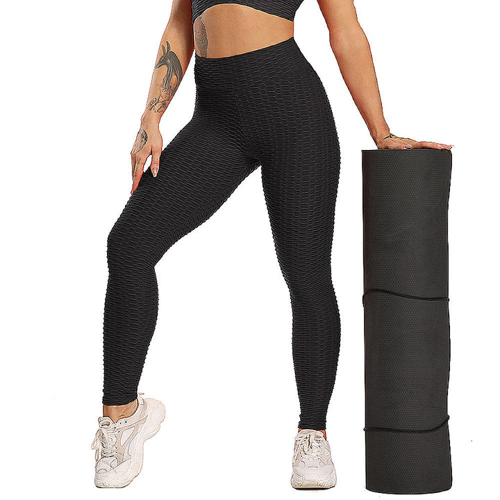 Frau in schwarzer Sportleggings mit Yogamatte, Fitnessmode, nahtlos, elastisch, bequem.