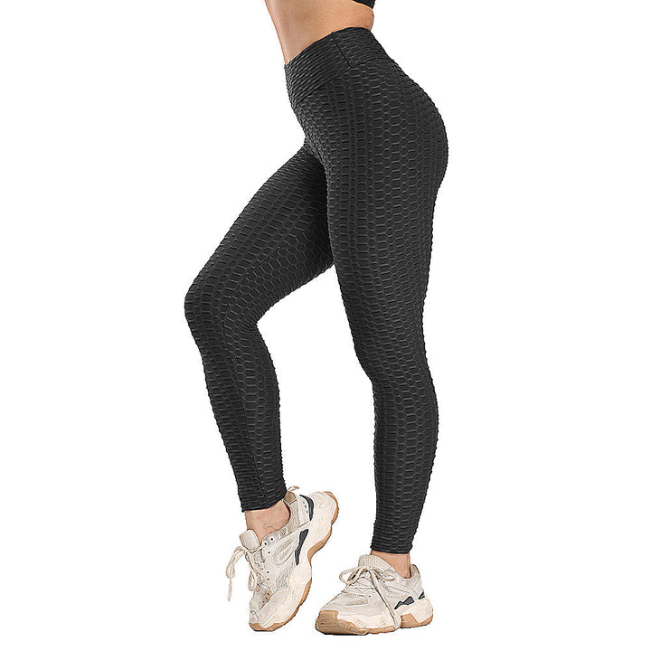 Frau in schwarzen, texturierten Leggings und weißen Sneakers, Sportbekleidung, Fitnessmode.
