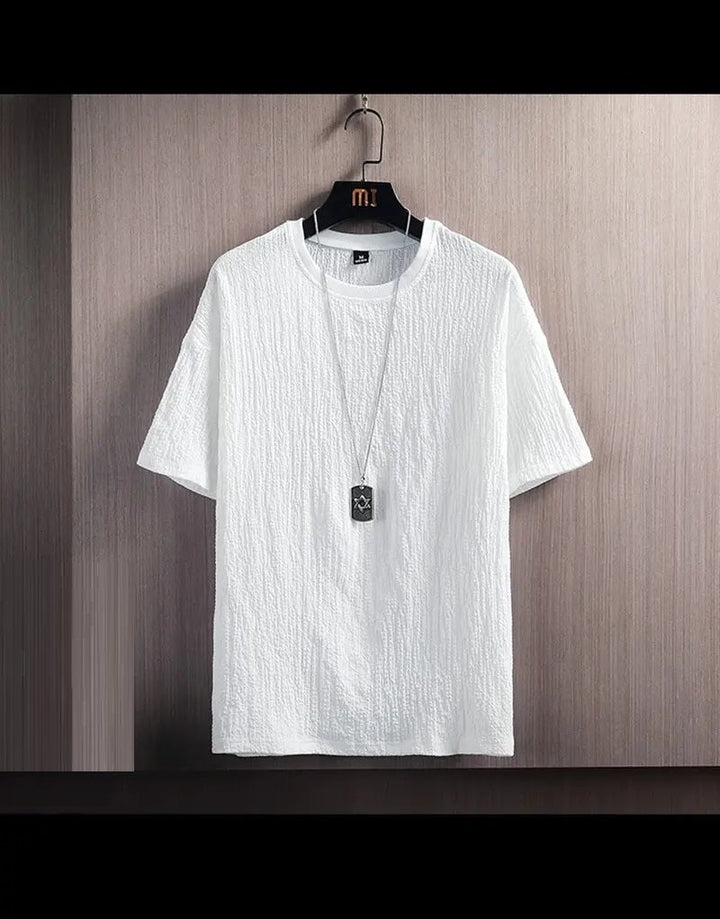 Weißes T-Shirt aus Baumwolle, kurzärmelig, strukturiert, auf Holzkleiderbügel hängend.