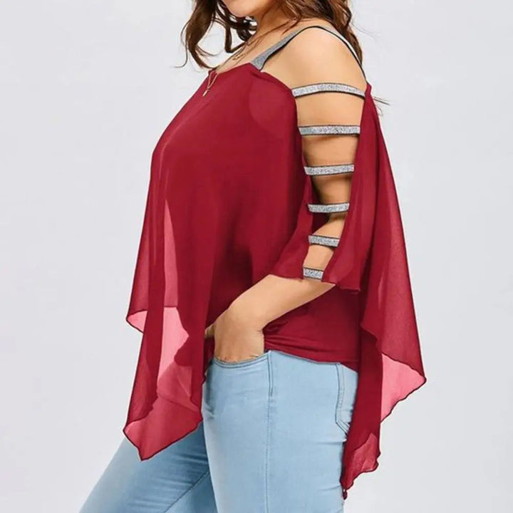 Frau in rotem, schulterfreiem Top mit Cut-Out-Ärmeln und blauer Jeans.