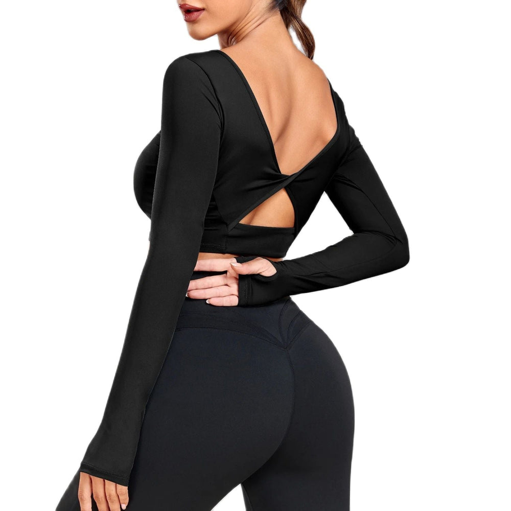 Frau in schwarzem, langärmligem Sporttop mit Rückenausschnitt, Yoga-Leggings, Fitnessmode.