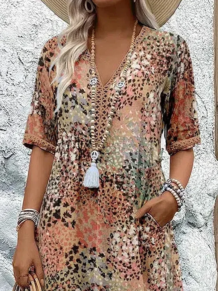 Close-up of the earthy speckled print dress on a model, showing the V-neckline with lace trim, gathered waist and side pocket. 6