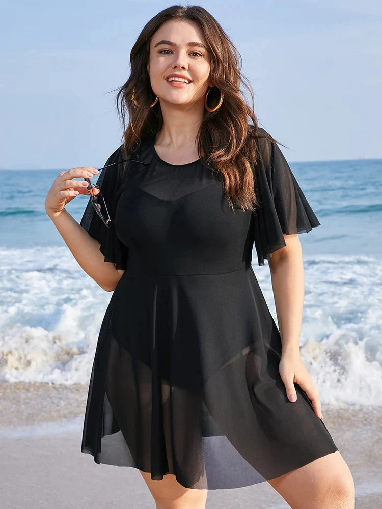 Frau im schwarzen Strandkleid am Meer, Plus-Size-Mode, Sommerkleidung, Strandhintergrund.