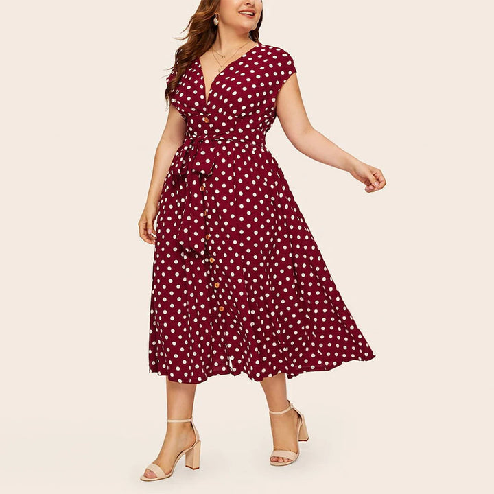 Frau in rotem gepunktetem Kleid, knielang, mit Gürtel, Sommermode, elegante Damenbekleidung.