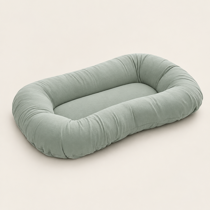 Empty sage green support pillow with a raised oval rim, shown at an angle on a cream background 8