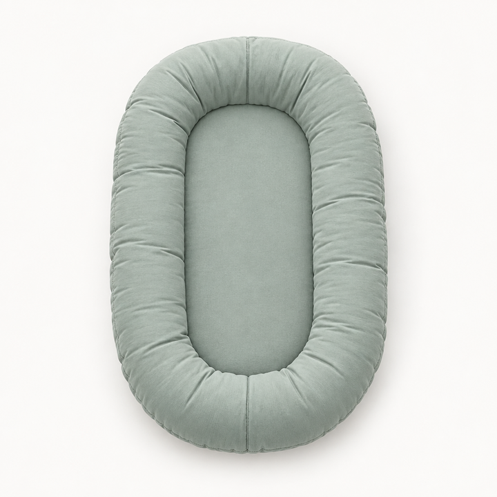 Empty sage-green oval pillow seen from above, showing the padded rim and flat center 8