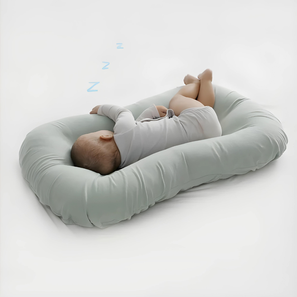 Baby sleeping on its side in a sage green cushion, with blue Z symbols above 4