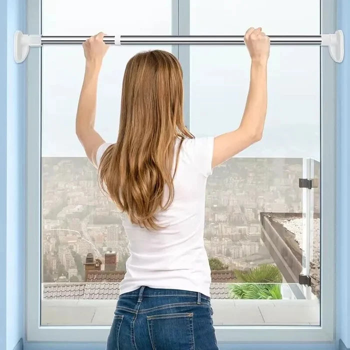 Silver stainless-steel tension rod mounted across a window frame without drilling