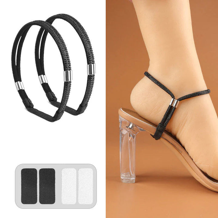 Pair of plain black textured elastic shoe straps with metal clasps and adhesive pads worn on a clear-heeled sandal.