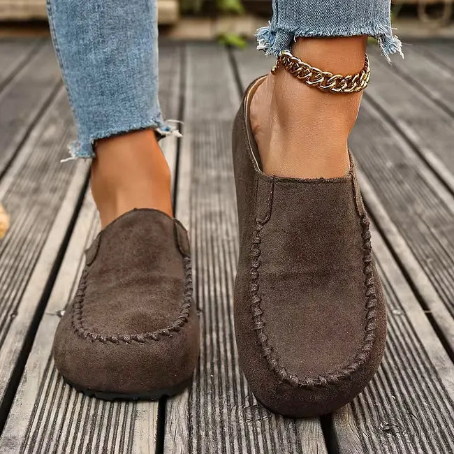 Brown leather slip-on sandals with stitched toe detail, front view.