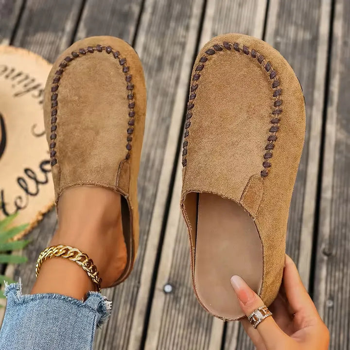 Brown leather slip-on sandals with a suede-like upper, top view with stitched detail.