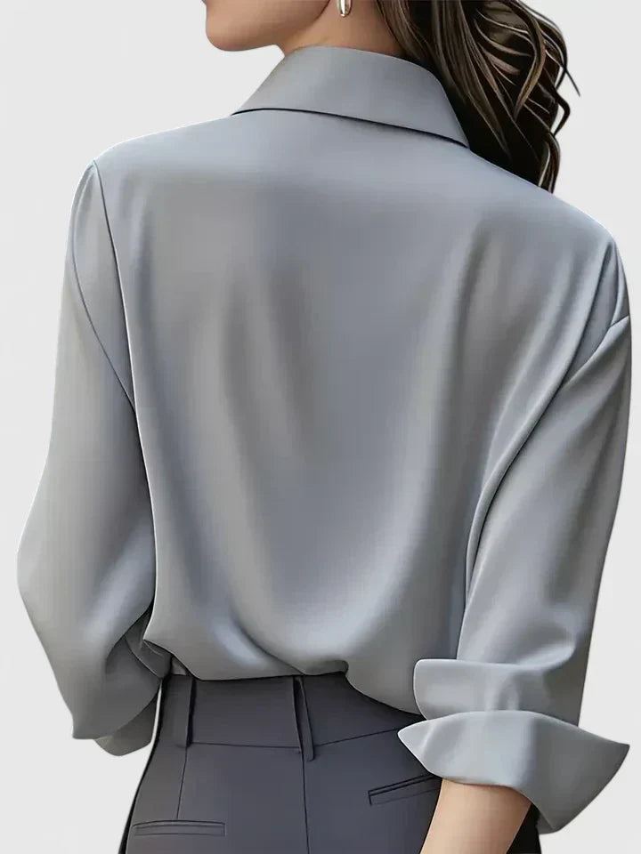 Back view of the gray blouse on a model, showing the relaxed drape, collar and turned-back cuff.