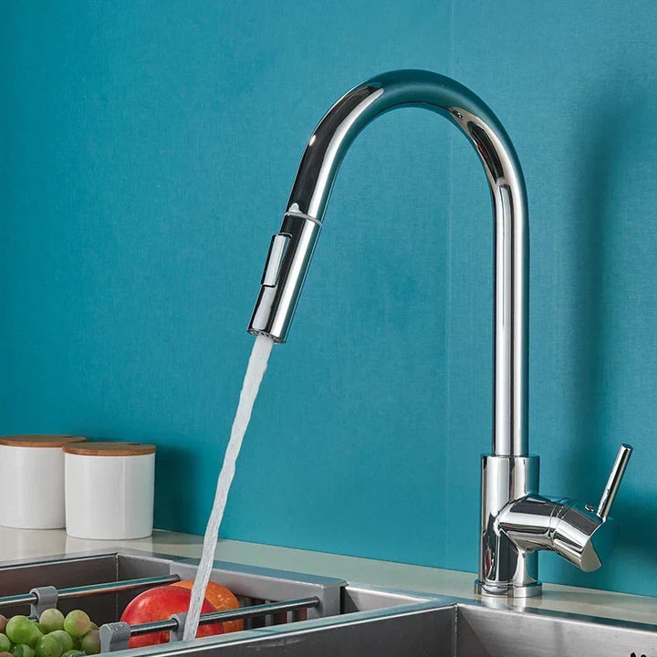 Chrome gooseneck faucet running water into a sink against a teal wall, fruit in a rack below 1