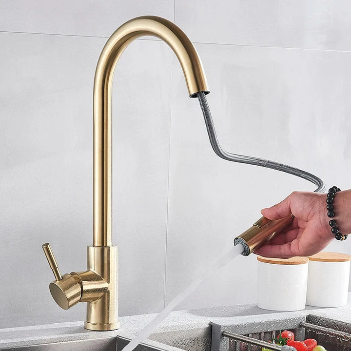 Brushed gold faucet with its spray head pulled out on a flexible hose, held by a hand 3