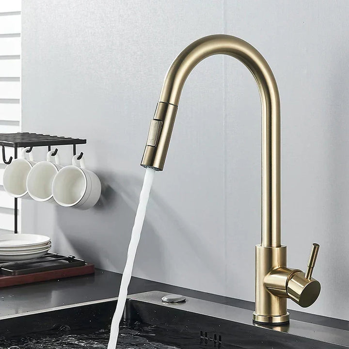 Brushed gold gooseneck faucet with side lever running water into a dark sink, mugs hanging nearby 6