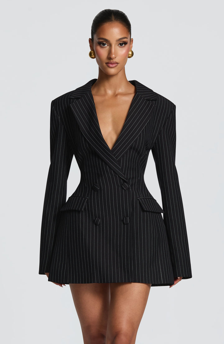 Black blazer dress in a white pinstripe pattern with a deep neckline and flared hem.