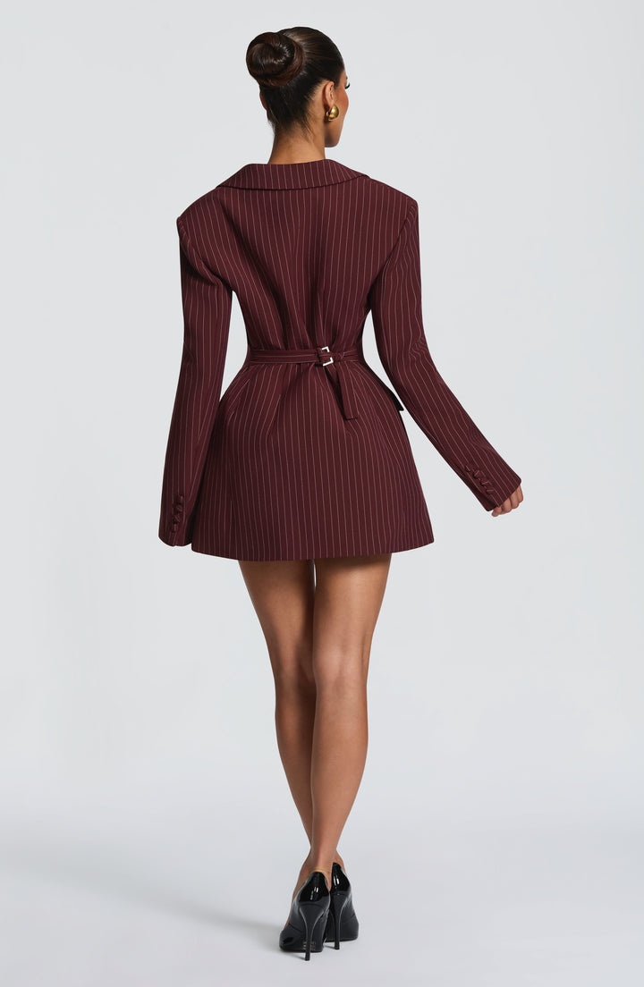 Back view of the burgundy pinstripe blazer dress with a belt buckled at the waist, a hair bun and black patent pumps. 29