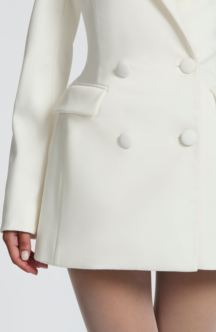 White blazer mini dress lower half with a flap pocket and clean hem, detail.