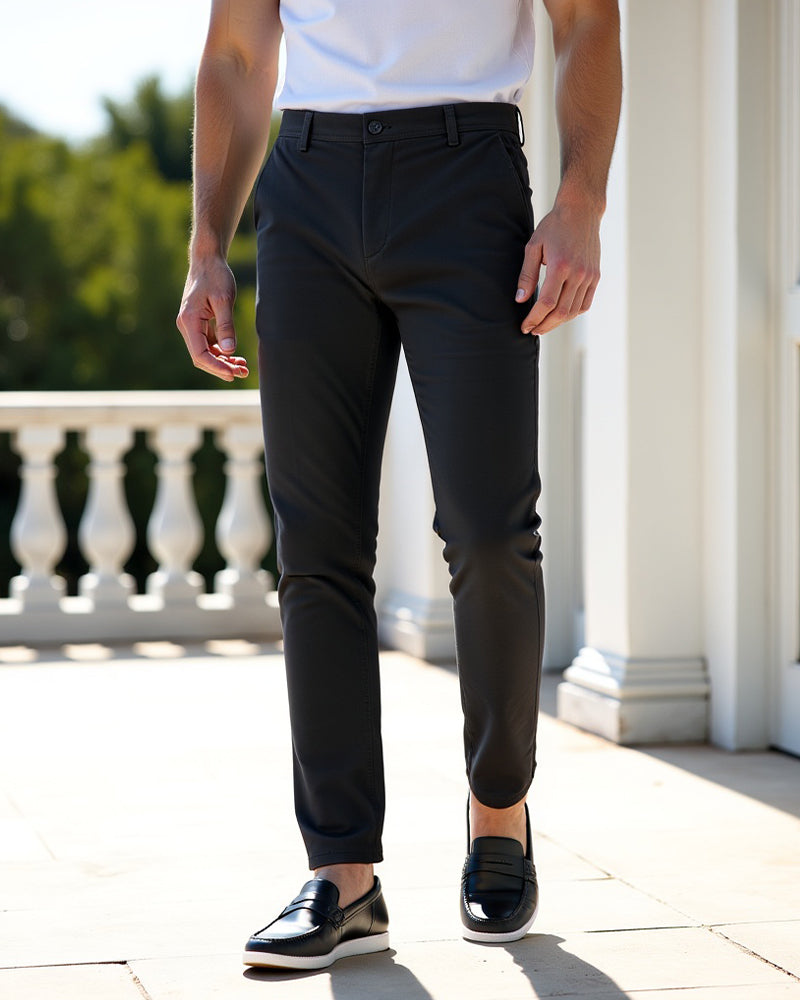 Charcoal chinos worn with a white tee and black leather loafers on a bright terrace with white columns and balusters. 7