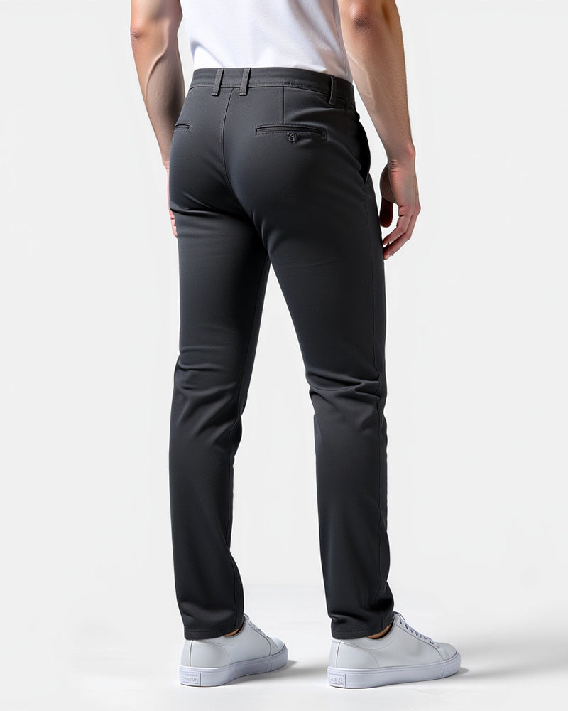 Back view of charcoal chinos showing buttoned back pockets and belt loops, worn with white sneakers on a plain light background. 8
