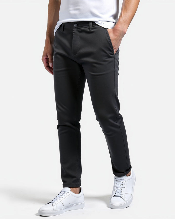 Charcoal chinos with rolled cuffs, three-quarter front view, worn with a white tee and white sneakers with one hand in the pocket. 12