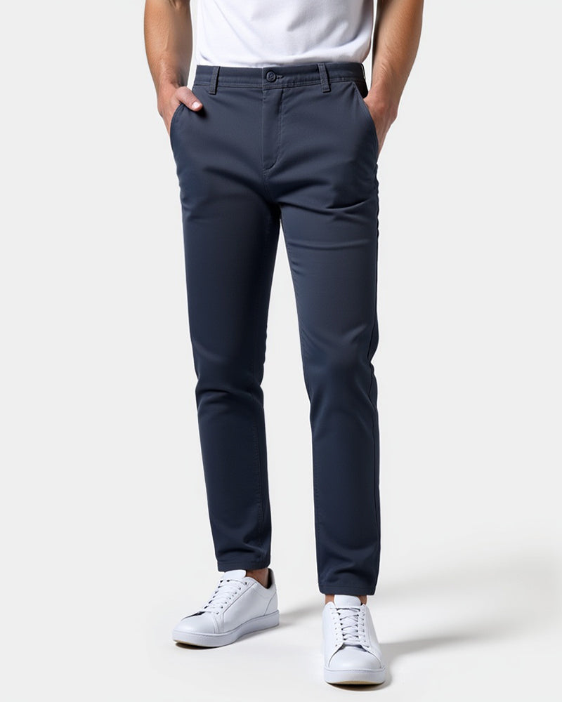 Front view of navy blue slim chinos worn with a white tee and white sneakers, both hands in the front pockets. 15