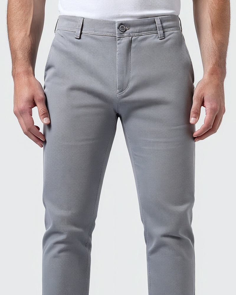 Close-up of the light gray chinos waistband showing the button closure, fly, belt loops and fabric texture on the thighs. 5