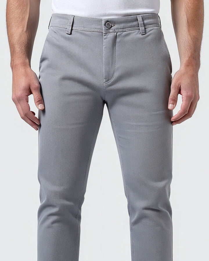 Close-up of the light gray chinos waistband showing the button closure, fly, belt loops and fabric texture on the thighs. 5