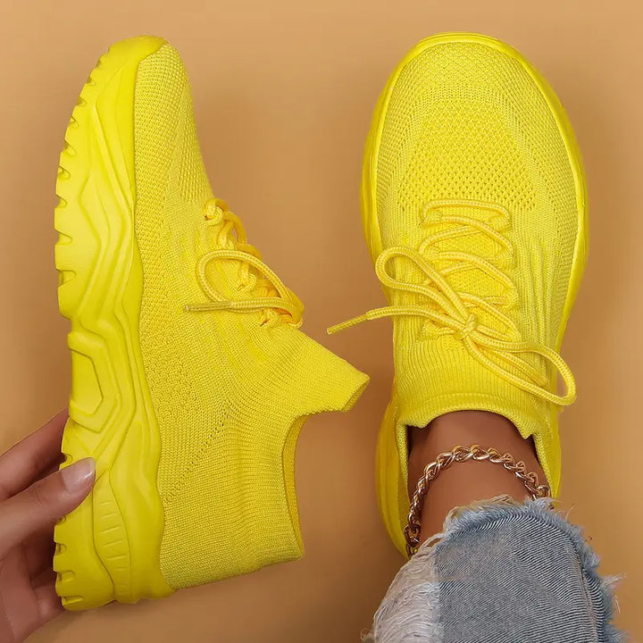 Solid yellow knit sneakers with yellow laces and chunky yellow soles, top-down view.