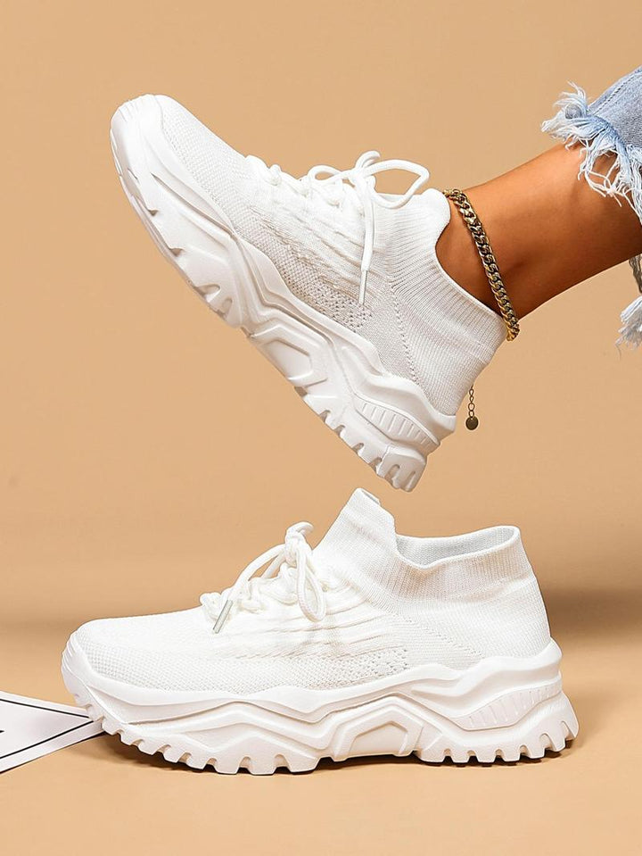 All-white knit sneakers with thick sculpted soles, top-down view.