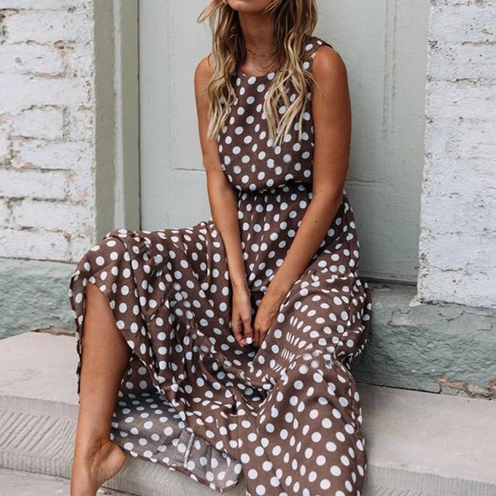 Woman with wavy hair sitting on stone steps wearing the brown polka dot dress with its flowing skirt 2