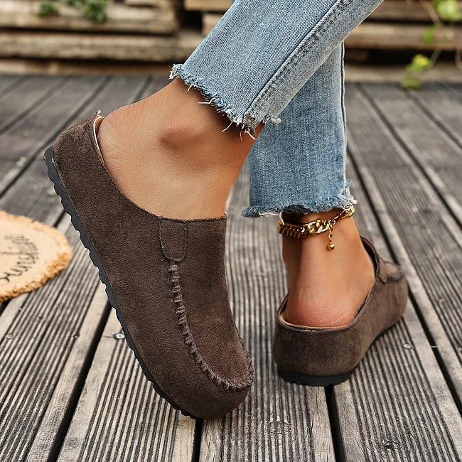 Brown leather slip-on sandals, side and back view with open heel and flat sole.