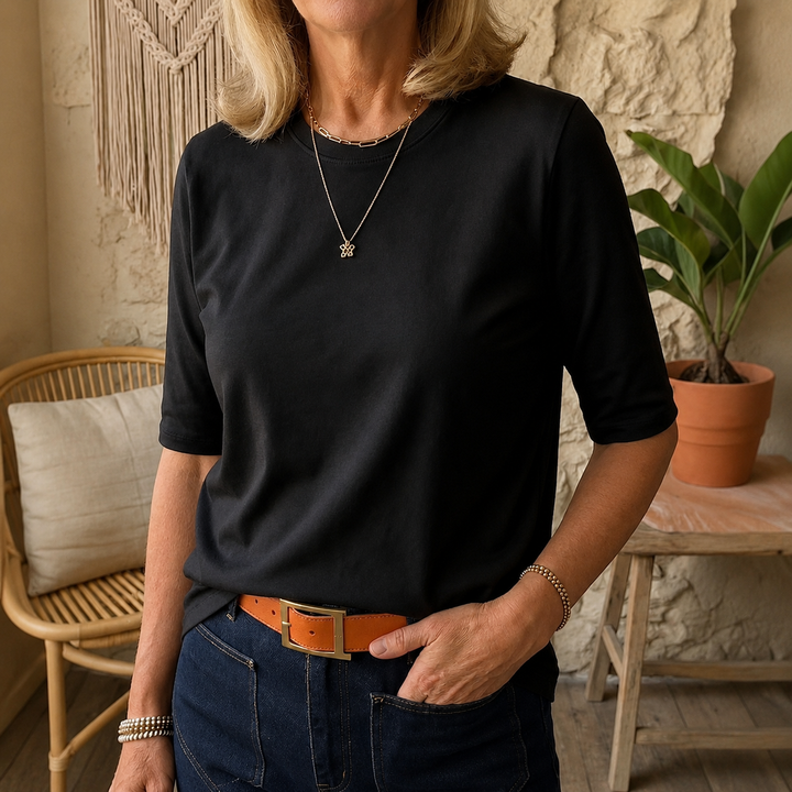 Woman wearing the black crew-neck tee with longer half sleeves and a curved hem, another view.