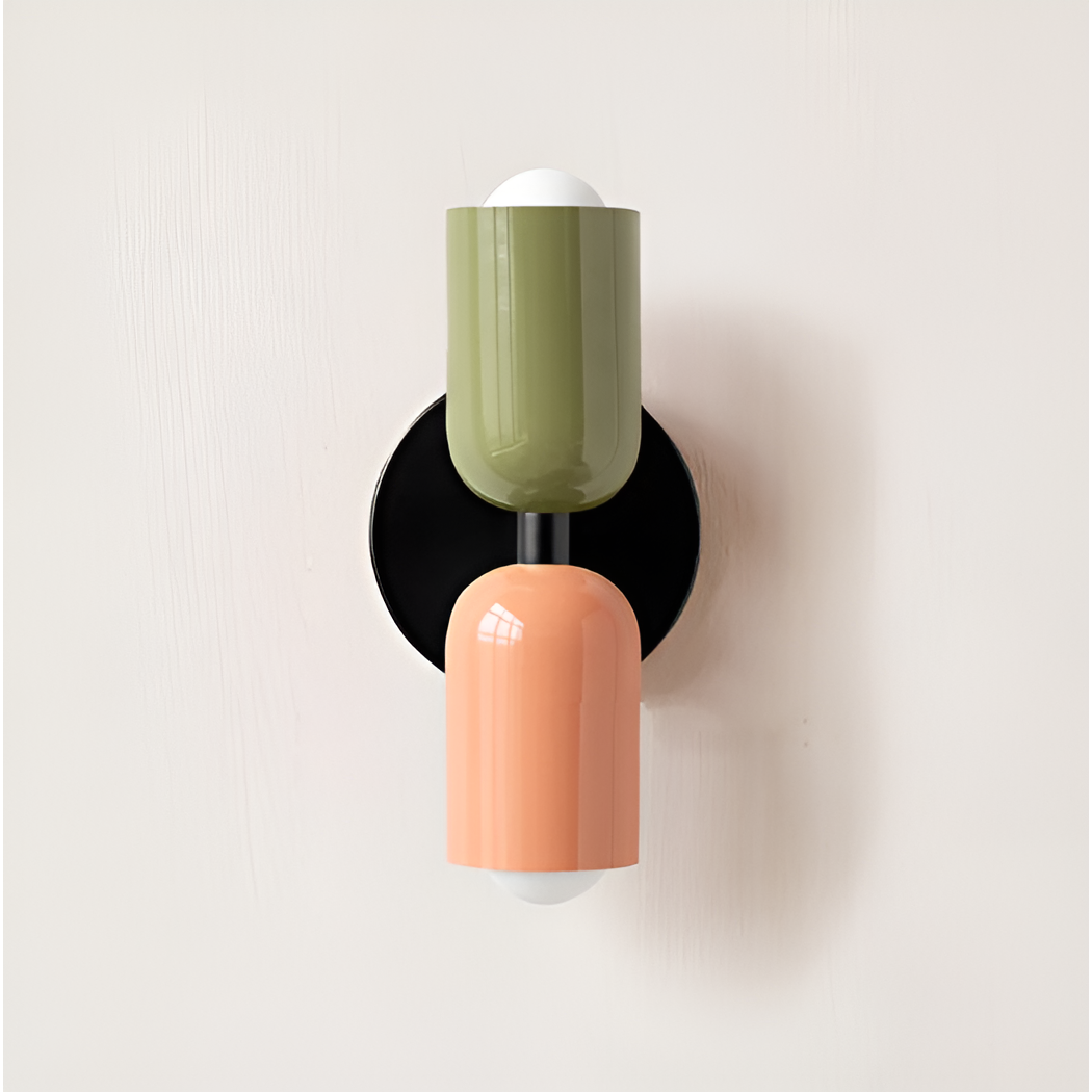 Close front view of a wall light with a green upper head and peach lower head on black backplate. 20