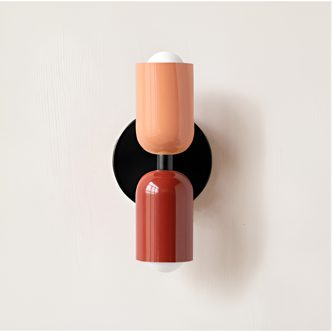 Wall light with a peach upper head and red lower head on a black round backplate. 18