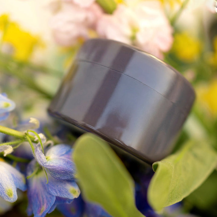 Dark gray round flower arranger vase insert among flowers and green leaves