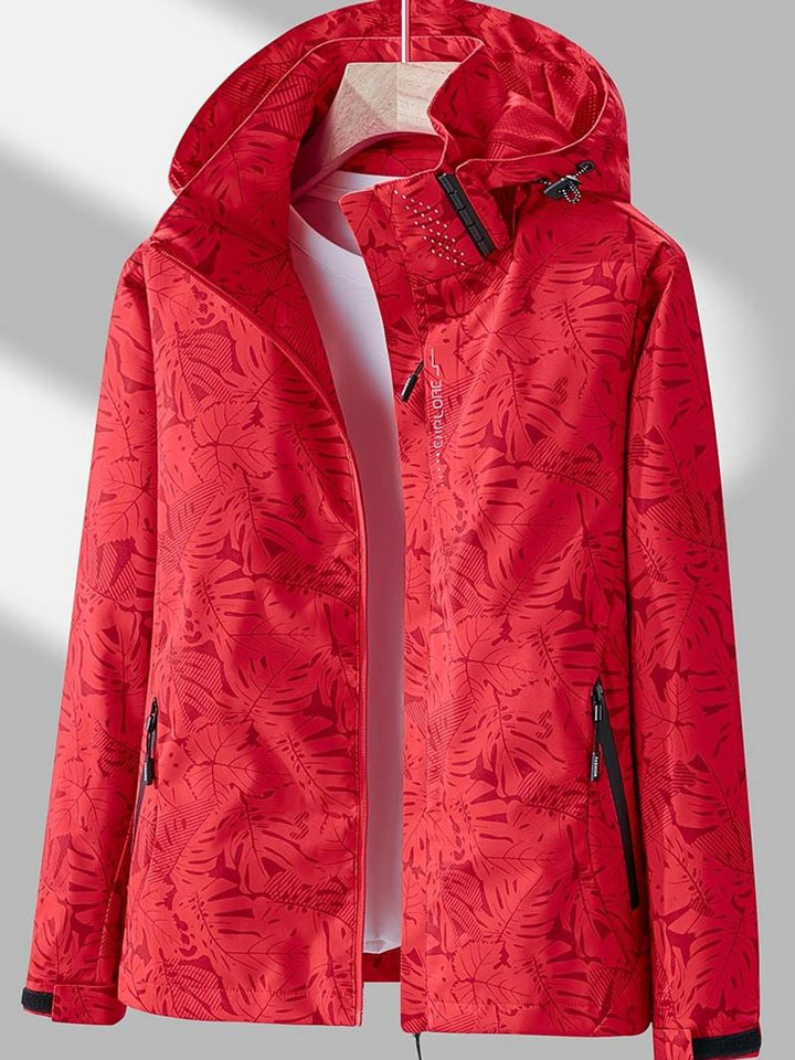 Red jacket with a darker red tropical leaf pattern, hood up on the hanger, with black-trimmed zip pockets and cuff tabs. 5