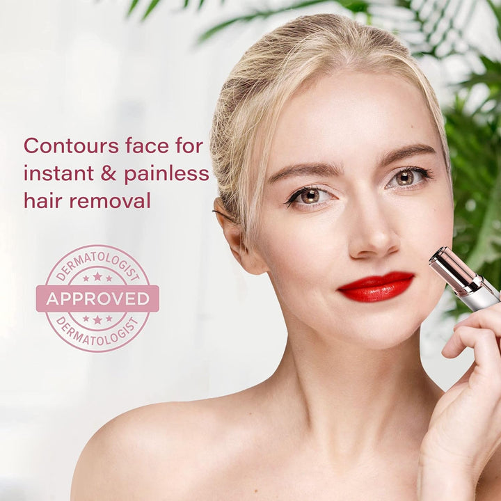 Blonde woman with red lipstick holding the white and rose gold hair remover against her cheek in front of green leaves.