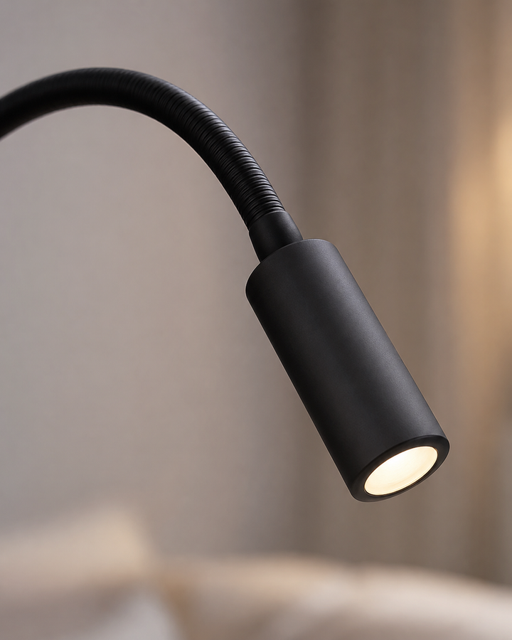 Detail of the black lamp head with its ribbed flexible neck and softly glowing LED.