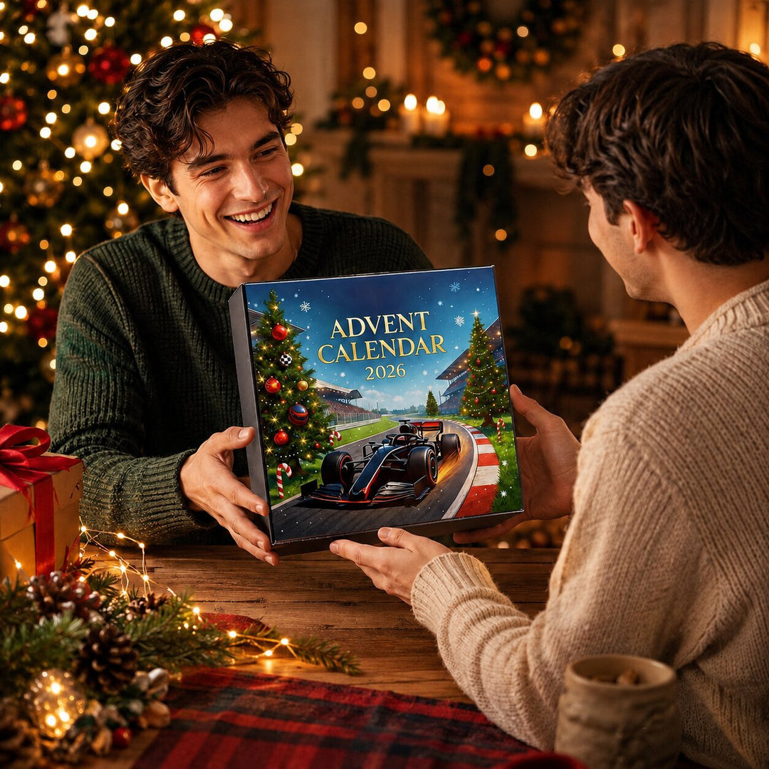 One man handing a race car advent calendar box to another man across a wooden table.