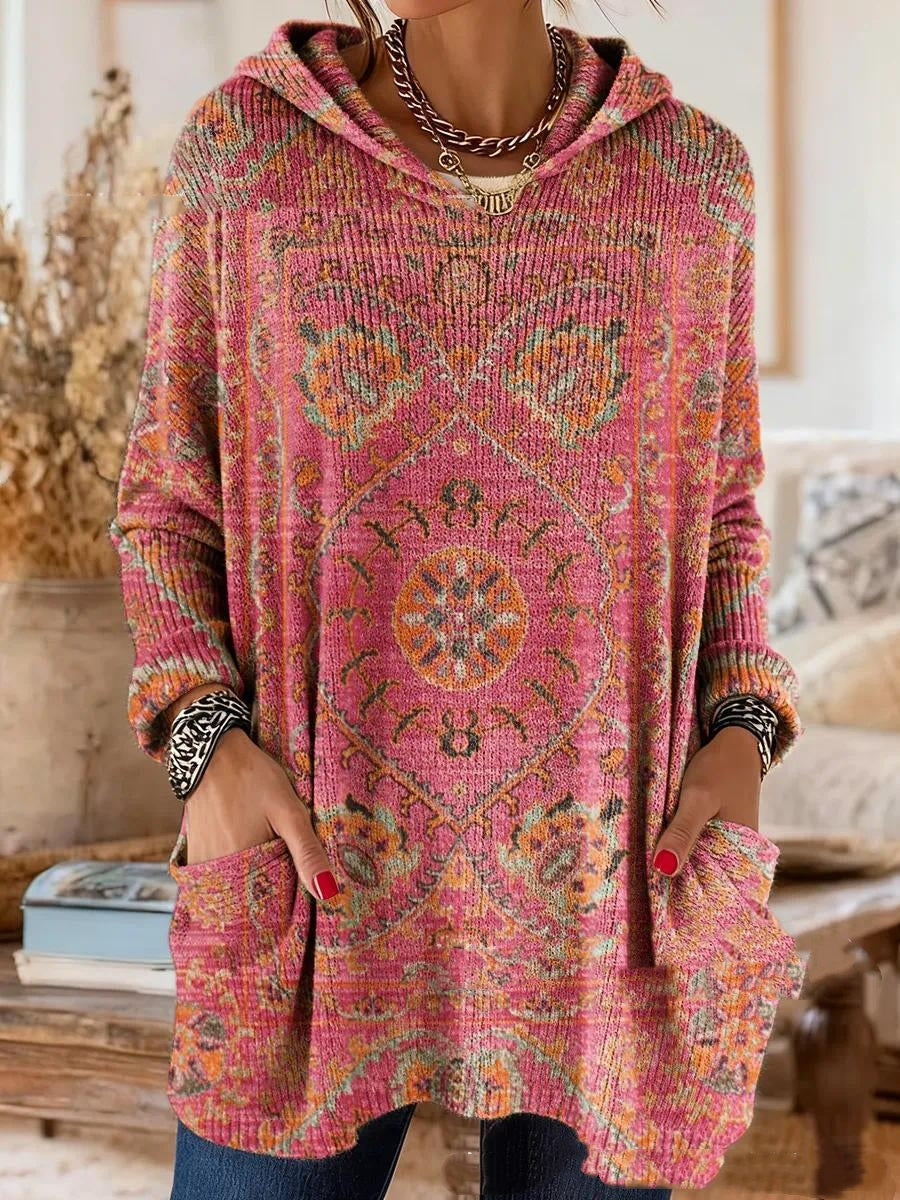Model wearing the hooded tunic in pink with an orange and green medallion print, loose long sleeves and deep front pockets. 6
