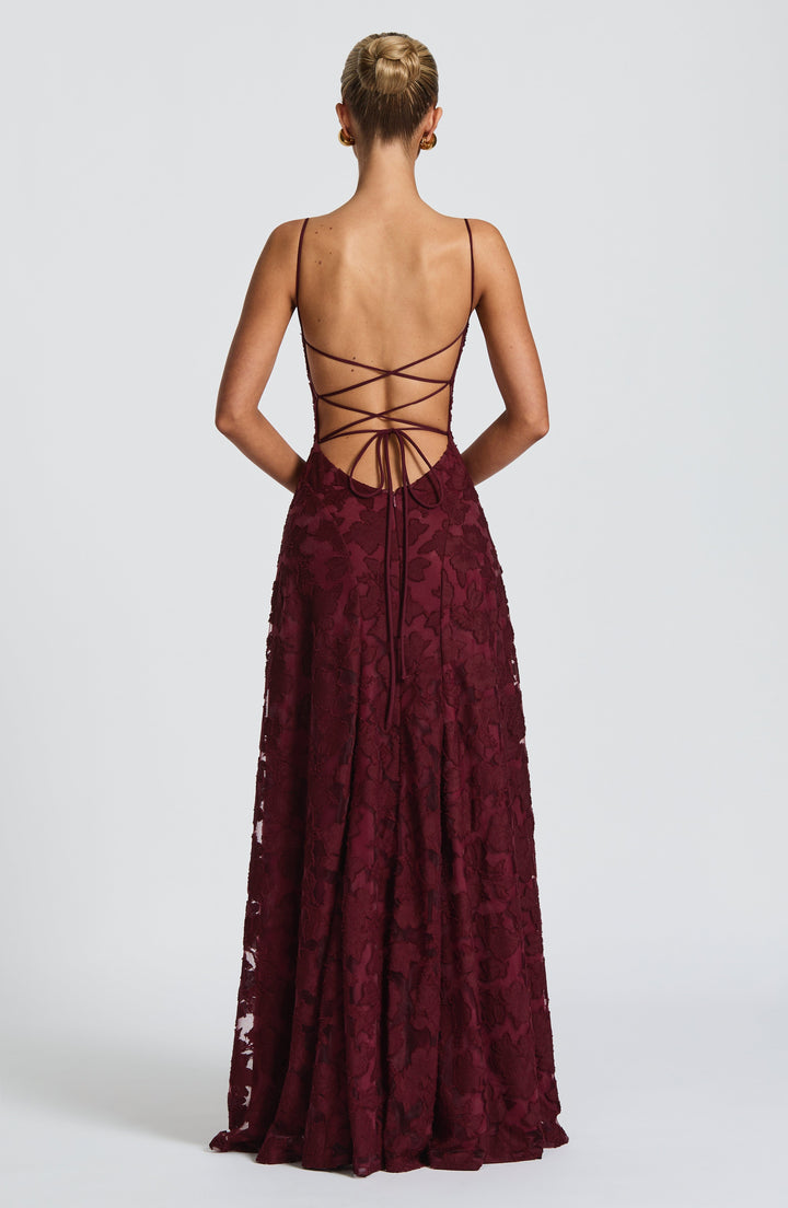 Back view of the burgundy gown showing criss-cross lace-up straps, a low open back and a tie at the waist. 23