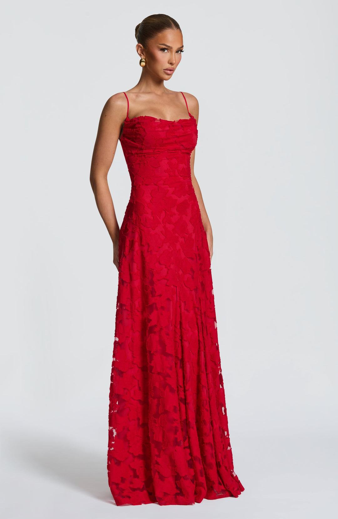 Three-quarter front view of the red textured floral gown on a model, showing the fitted bodice and sheer panels in the skirt. 25