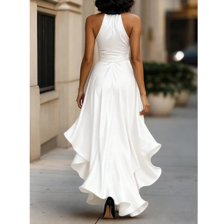 Women's white satin dress, back view, showing the halter back, waist seam and layered ruffle sweeping behind the model.