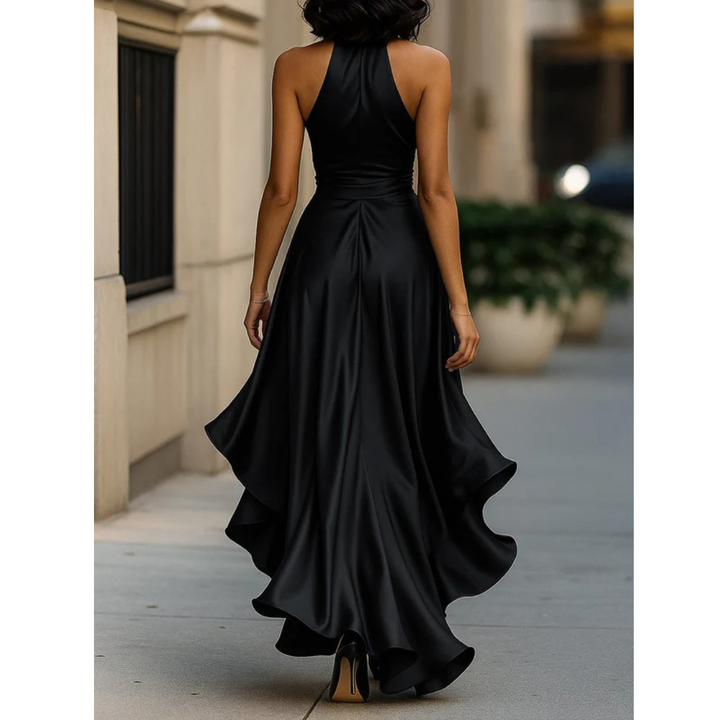 Women's black satin dress, back view, showing the halter neck, fitted waist and ruffled hem that trails behind.