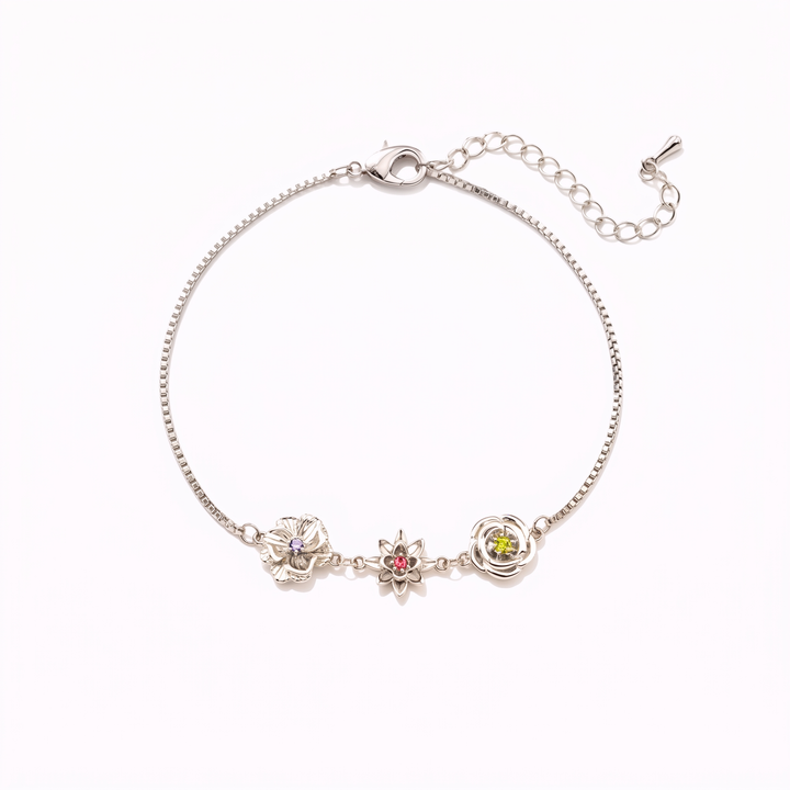 Silver-tone birth flower bracelet with three flower charms and an extender chain, laid flat on white.